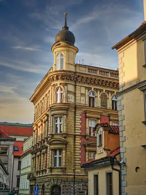 Ornate neoclassical corner building with a domed turret in Prague's old town at golden hour