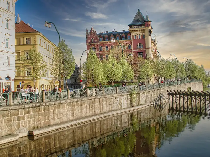 Vltava river embankment in Prague with an ornate red building