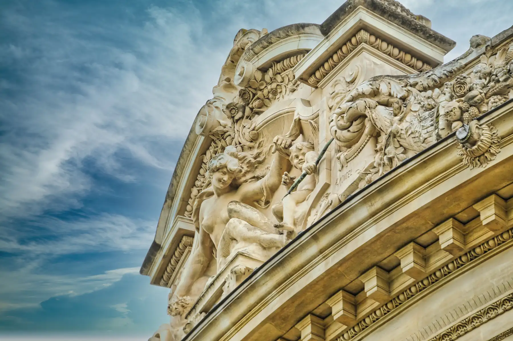 Ornate sculpted figures and floral stone carvings on the facade of the Louvre Palace in Paris