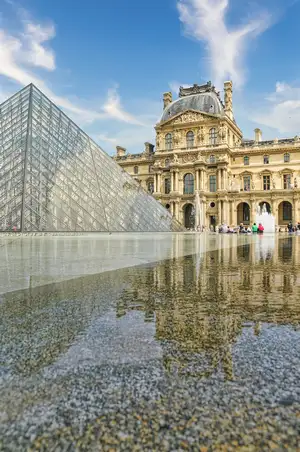 Glass pyramid and the historic palace of the Louvre art museum reflected in water in Paris