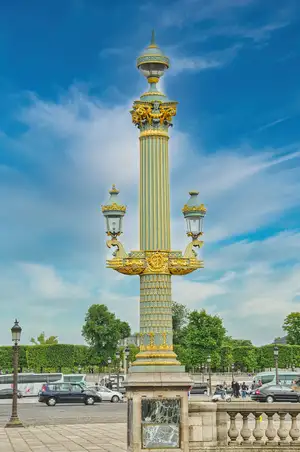 Ornate gilded lamp post at the Place de la Concorde in Paris with traffic and gardens behind