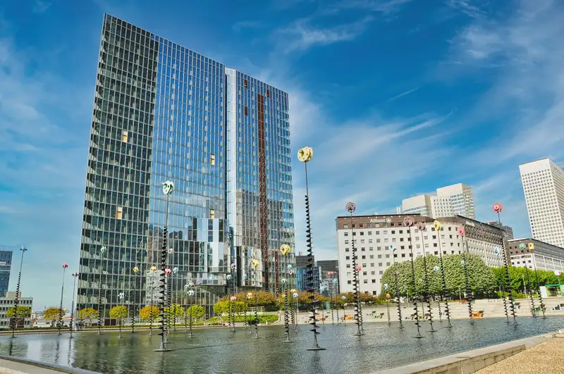 A modern glass tower above the sculpture pool at La Défense in Paris