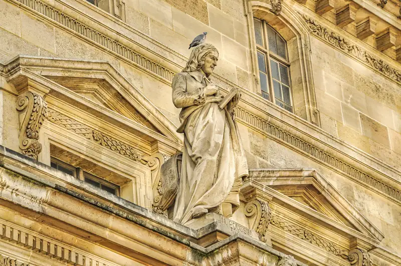 Detail of the Nicolas Poussin statue on the walls of the Louvre in Paris