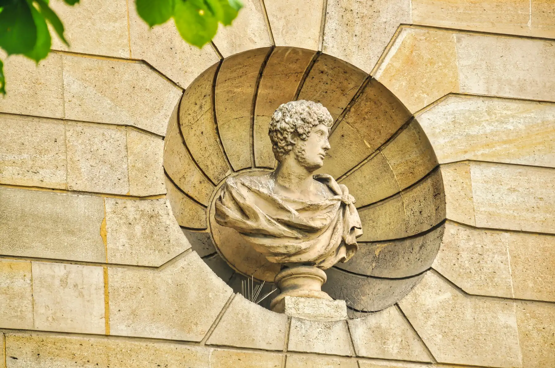 A classical portrait sculpture in a stone wall in Paris