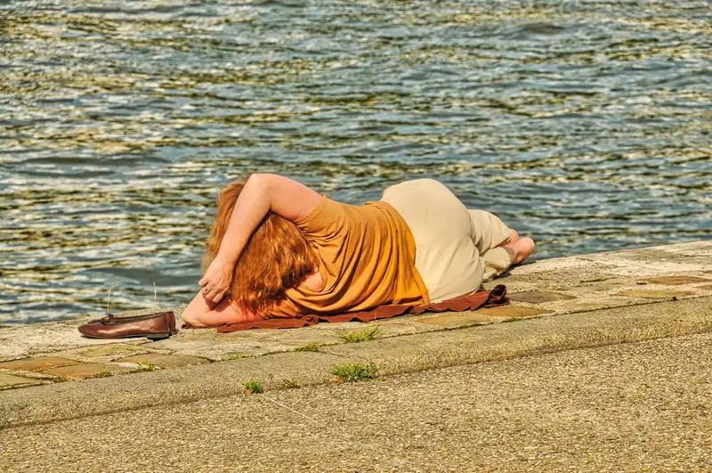 A woman resting on the stone quay beside the water in Paris