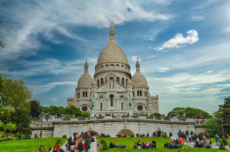The white Sacré-Cœur basilica above the green lawns of Montmartre in Paris