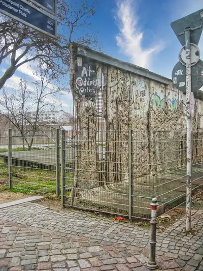 A preserved graffiti-covered section of the Berlin Wall behind a protective fence