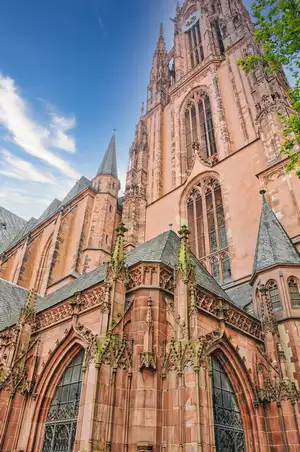 The red sandstone Gothic facade and tower of Frankfurt Cathedral rising against the sky in Germany
