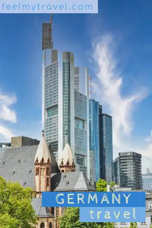Modern glass skyscrapers rising behind a historic stone church in the Frankfurt skyline, Germany