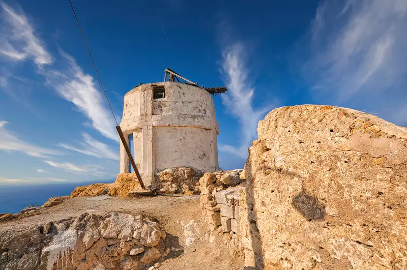 Traditional old windmill in Anafi standing on a rocky hilltop above the Aegean