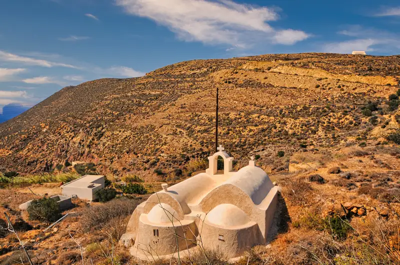 Small whitewashed chapel with a curved roof set on Anafi's open hillside