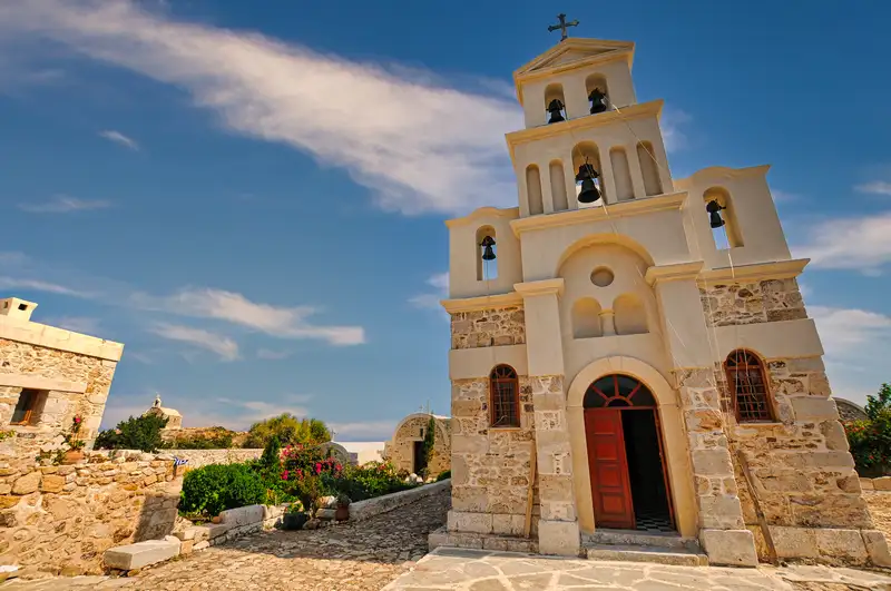Bell tower of the Zoodochos Pigi Monastery in Anafi with stone walls and a red wooden door