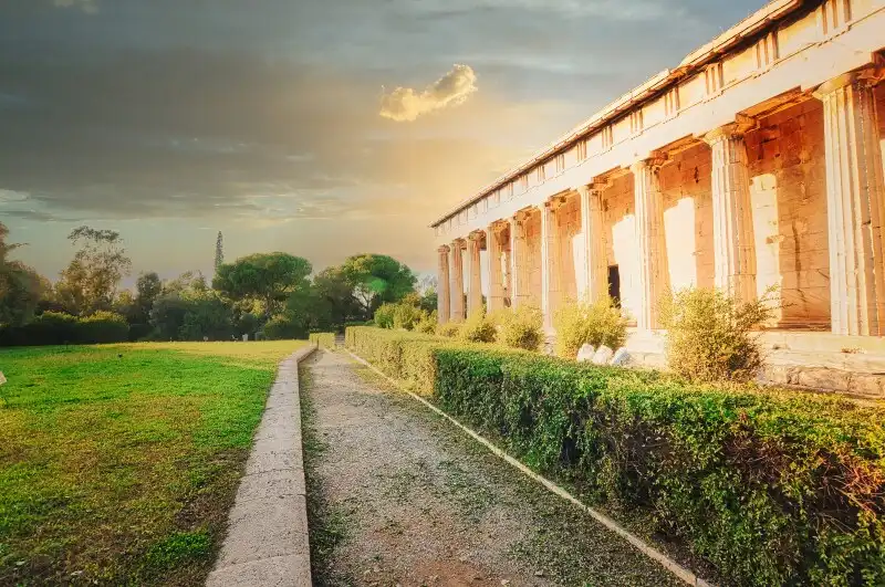 The Temple of Hephaestus in the Ancient Agora of Athens surrounded by green lawns and hedges with trees in the background