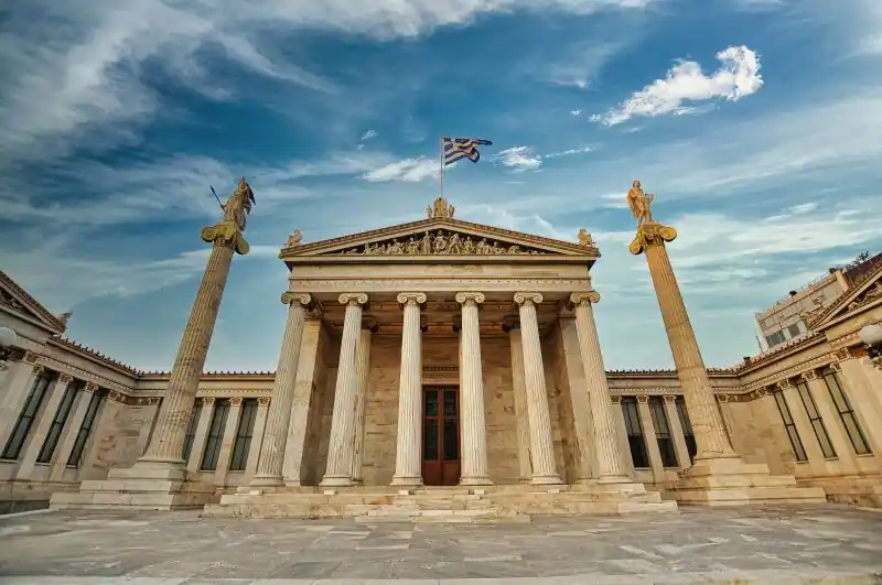 The facade of the Academy of Athens with Ionic columns, a painted pediment, and statues of Athena and Apollo on tall pillars