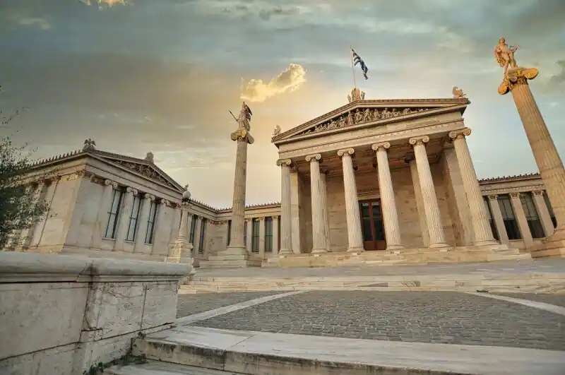 The Academy of Athens with its marble columns and statues of Athena and Apollo on tall pedestals, part of the Athenian Trilogy on Panepistimiou Street