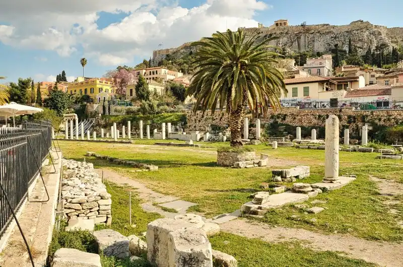 Roman Agora Athens panoramic view ruins columns palm tree Acropolis background Greece