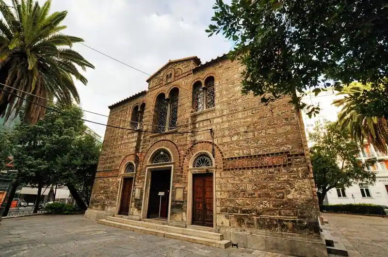 The Byzantine church of Sotira Lykodimou in Athens surrounded by palm trees and city buildings