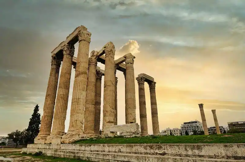 The towering Corinthian columns of the Temple of Olympian Zeus in Athens standing against the sky with the modern city visible in the background