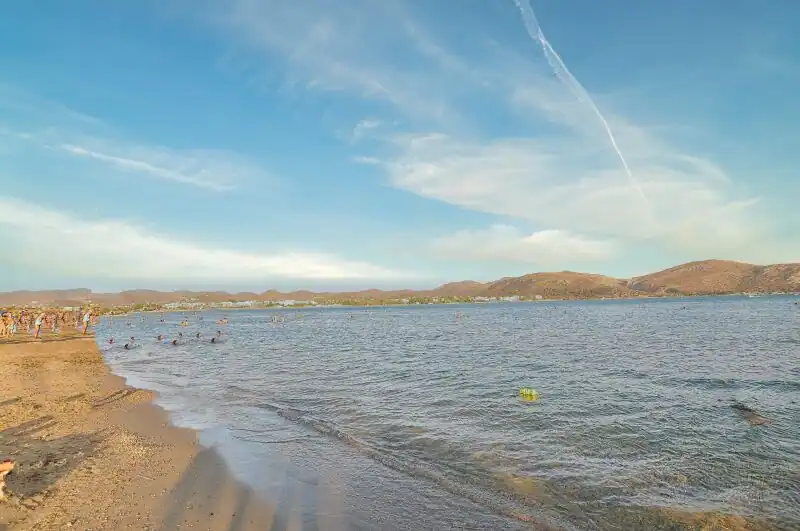 Anavissos beach near Athens with swimmers in the calm bay and hills of the Attic coastline in the background