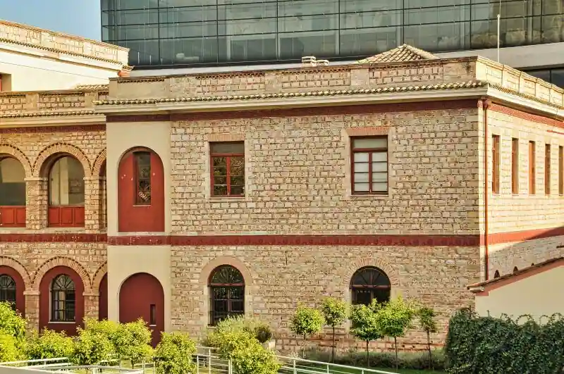 Exterior of the Acropolis Museum in Athens showing the modern glass building and a preserved neoclassical house