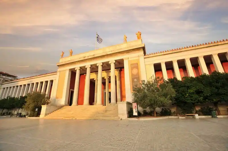 National Archaeological Museum of Athens neoclassical facade with columns and Greek flag at sunset