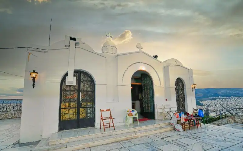 Front view of Agios Georgios church on top of Lycabettus Hill with the entrance doors open at dusk
