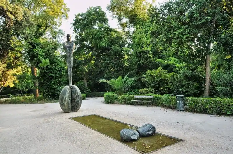 Modern sculpture and water feature surrounded by lush green trees in the National Garden of Athens