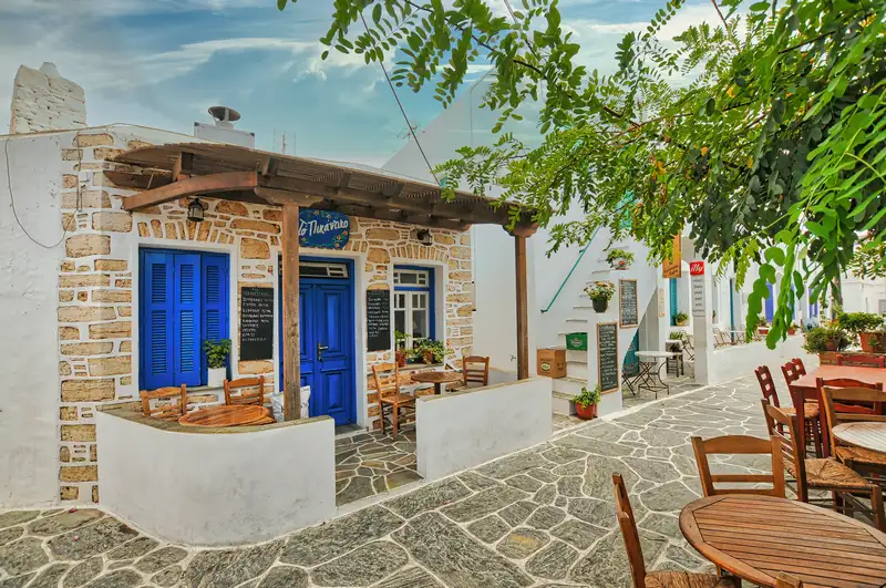 Traditional café in Chora Folegandros with blue doors and stone-paved street