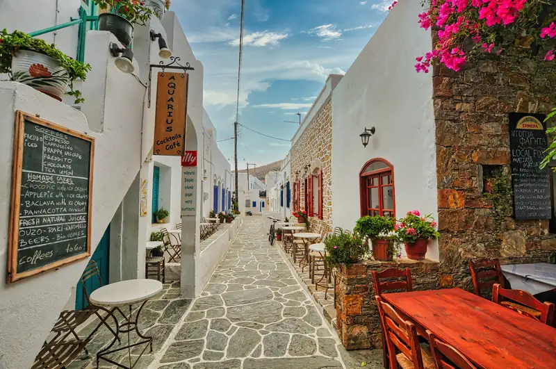 Inside Chora Folegandros with narrow stone alley, cafés, and bougainvillea