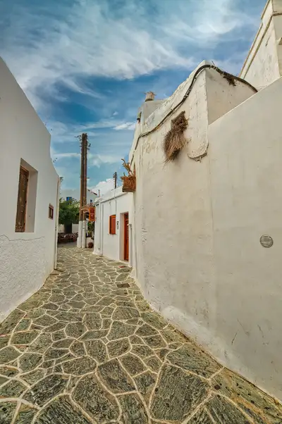 Narrow pathway in Chora Folegandros with whitewashed walls and stone paving