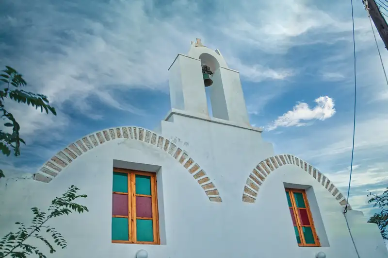 Whitewashed church in Chora Folegandros with a bell tower against the sky