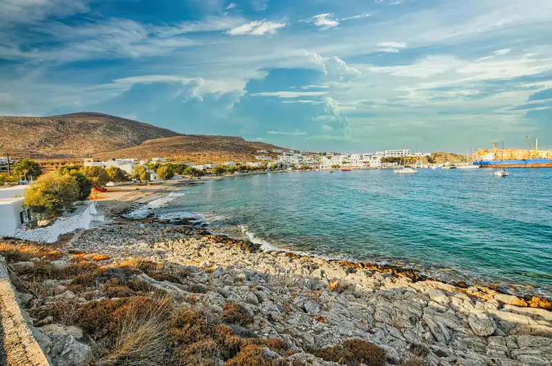 Karavostasis port folegandros with rocky shore, turquoise bay, and ferry in the distance