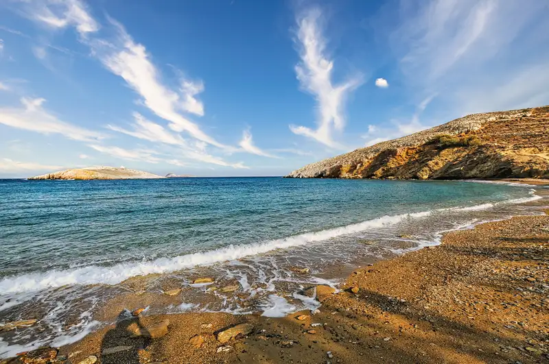Livadi beach folegandros with sandy shore, small waves, and hills across the bay