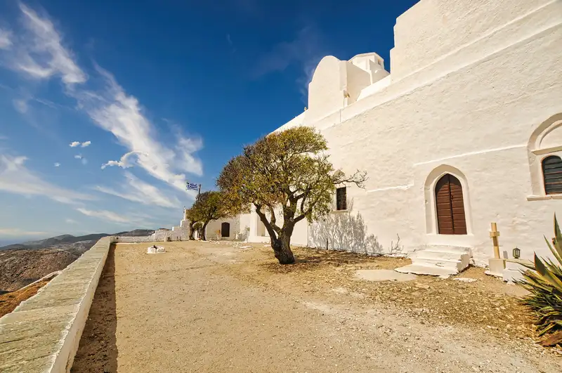 Panagia church folegandros on the hilltop with a single tree and stone courtyard