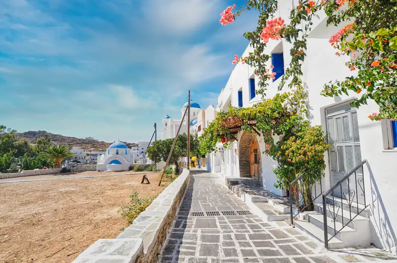 Cycladic architecture in Chora of Ios, with whitewashed houses, stone steps, and a blue-domed chapel
