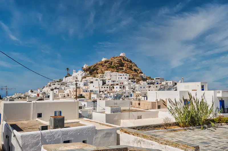 Chora of Ios spread across a hillside, with the rocky summit rising above the village