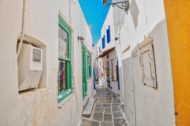 Whitewashed alley in Chora village on Ios island, with colourful shutters and old stone paving