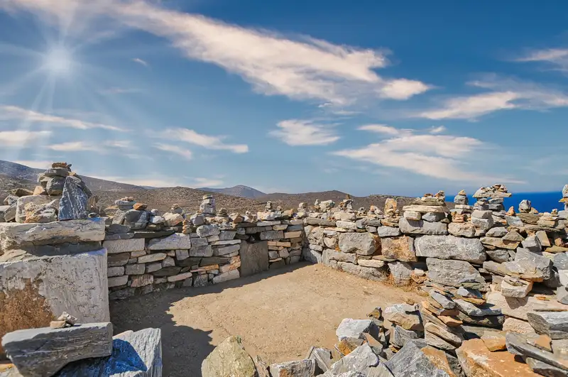 The ruins of Homer's tomb at Plakotos on Ios, with stacked stones and a wide sea horizon