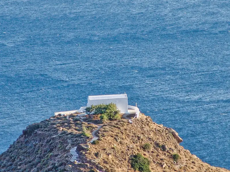 A small whitewashed chapel on a rocky cape above the Aegean Sea on Milos island
