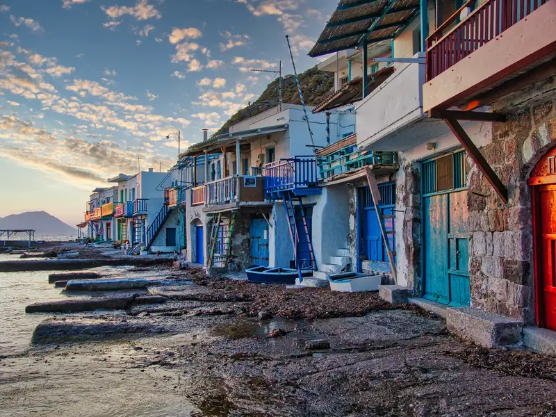 A row of colorful syrmata boat houses along the shore of Klima village