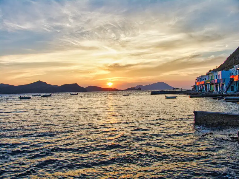 Sunset over the bay of Klima village with small fishing boats on Milos island