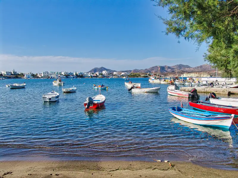 The small harbor of Pollonia village with fishing boats and the whitewashed houses of the seaside settlement