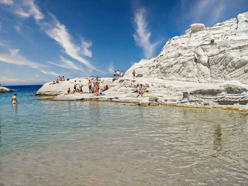People swimming and resting on the white volcanic rocks of Sarakiniko beach on Milos island