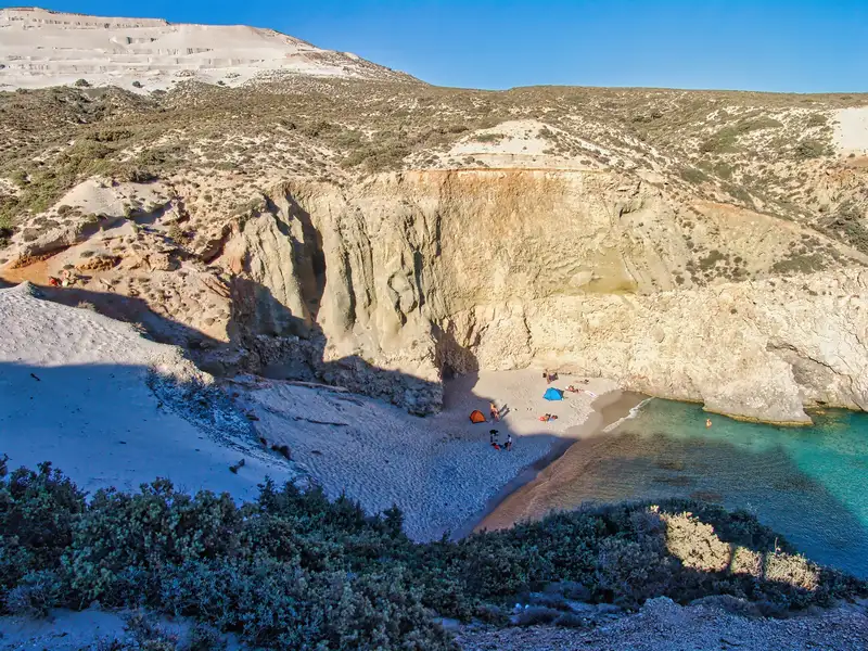  view of the small hidden beach of Tsigrado with high cliffs and white sand on the south coast of Milos island