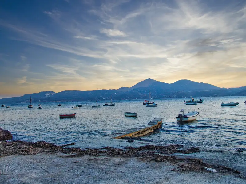 A view from Klima village over the bay of Milos with small fishing boats and distant mountains at sunset