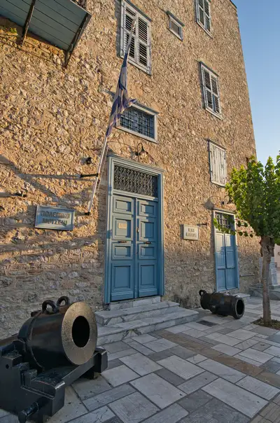 Entrance of the War Museum of Nafplio with old cannons and Greek flag