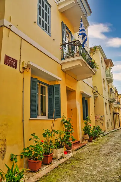 Yellow neoclassical house with green shutters and a Greek flag in old town Nafplio