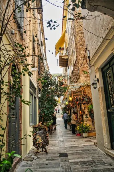 Narrow alley in the old town of Nafplio with cafes and plants
