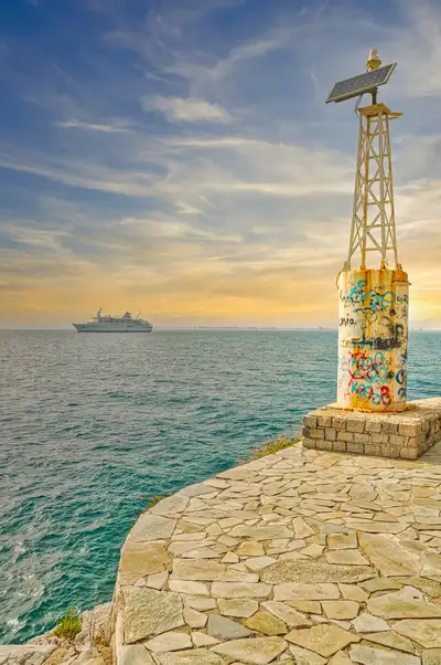 Stone promenade and harbour light at the edge of Nafplio with sea view
