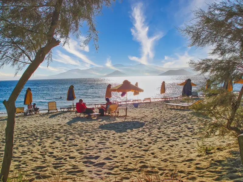 Sun loungers and umbrellas at Agia Anna beach Naxos with the coastline in the distance